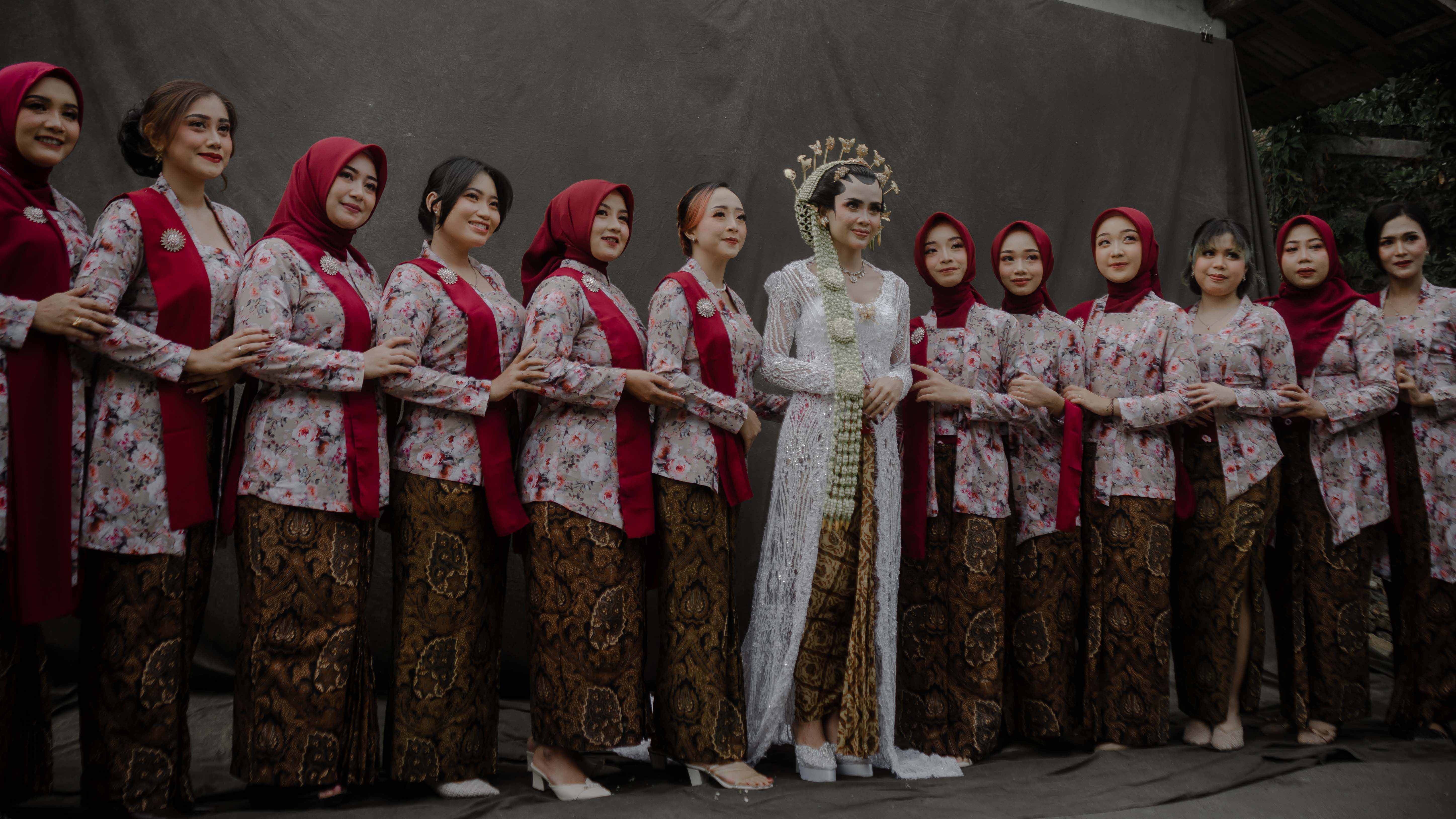 Pengantin wanita bersama orang tua di bawah rangkaian bunga